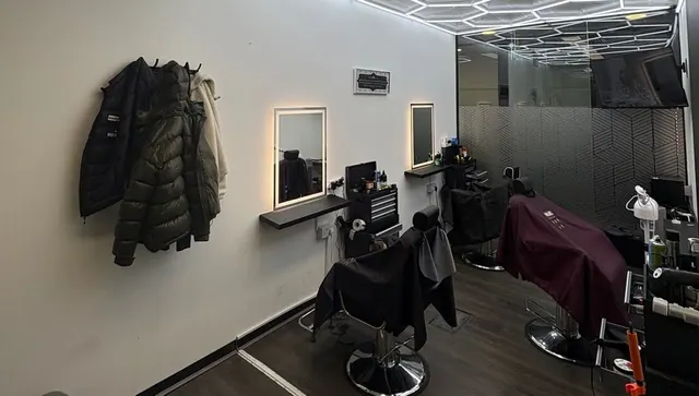 The shop: lit mirrors, two barber chairs and a tool trolley