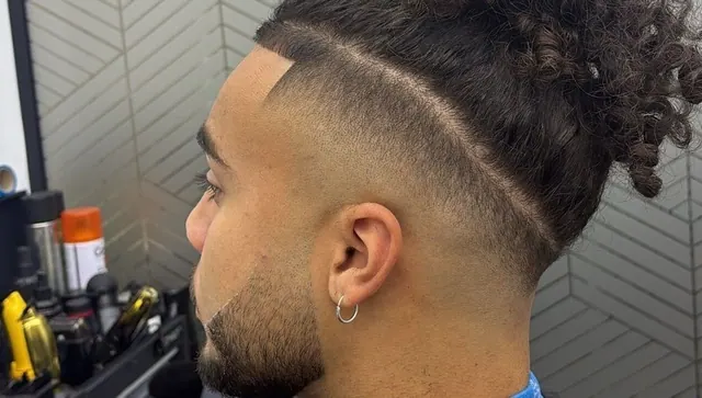 A slick-back with a skin fade, a part line and a shaped beard