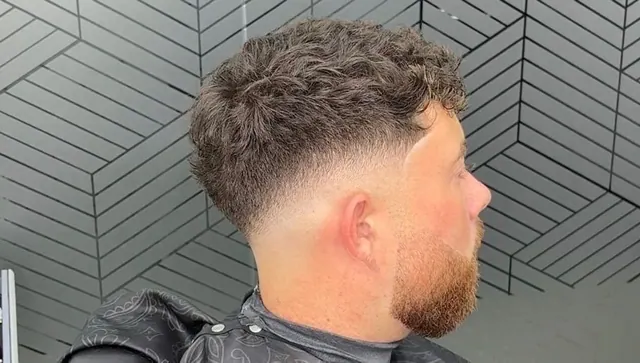 A curly crop with a skin fade and a beard